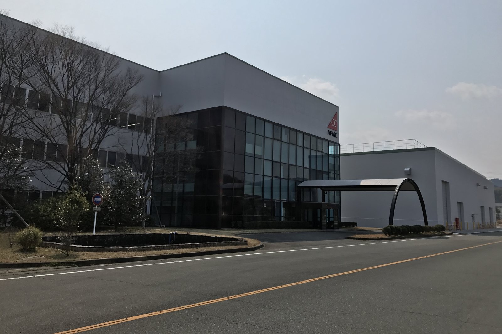 ガラス張りの入口がある、グレーの大きな工場